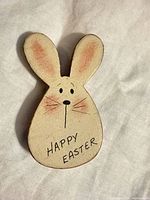Front view of wooden Easter bunny brooch showing Happy Easter text and facial details