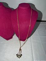 Full view of necklace on display bust showing twin chains and tassel drop