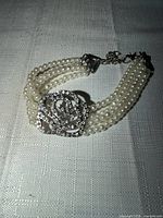 Full view of bracelet showing four strands of pearls and diamond flower centerpiece