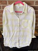Front view of blouse showing color, pattern, pocket, button front, gathered hem