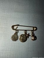 Full view of safety-pin brooch with four charms hanging
