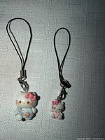 Two Hello Kitty smartphone charms showing size difference and cord loops