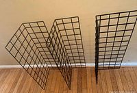 Three black wire shelving panels standing upright