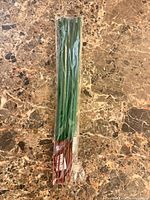 Entire sealed pack of 12 green/red incense sticks on marble surface