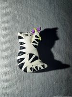 Front view of white cat pin with black stripes and purple butterfly