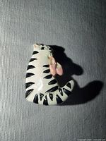 Front view of ceramic cat brooch showing black stripes and pink shoes
