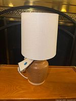 Full view of brown ceramic lamp with white drum shade