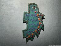 Front view showing dinosaur shape, teal color, glitter border, painted details