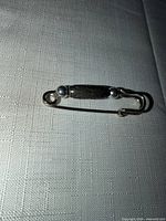 Full view of silver-tone safety-pin brooch on fabric backdrop