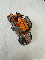 Mudflap figure in partial vehicle mode, showing orange and black compact car form