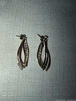Front view of earrings showing tri-tone interlaced strands and texture