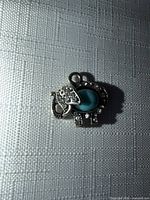 Front view of elephant pendant showing turquoise-color cabochon and rhinestone accents