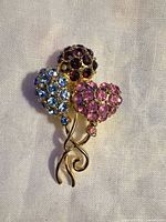 Front view of gold-tone brooch showing three rhinestone balloons and intertwined stems