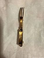 Front view of gold tone fork brooch