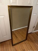 Full view of gold framed mirror leaning against door