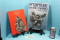 Front view of both books upright beside soda can for scale