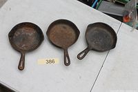 Top view of three small cast iron fry pans showing interior surfaces with rust