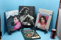 All four hardcover books on stands with can for scale