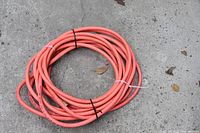 Coiled 50' orange air hose on concrete surface