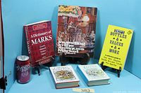 Five hardcover books displayed upright and flat with Dr Pepper can for scale