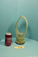 Front view of green and white swirled art glass vase beside soda can for scale