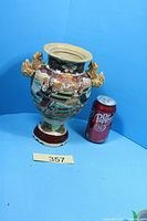 Front view of multicolour moriage vase beside soda can for scale