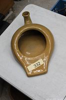 Top view of tan glazed ceramic bedpan with spout and handle