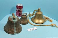 All three brass bells beside soda can for scale