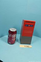 Front view of Canada Post letter box coin bank next to soda can for scale