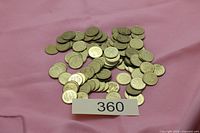 Pile of over 100 brass-tone Chuck E. Cheese tokens on pink cloth