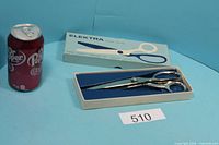 Shears in box next to soda can for scale