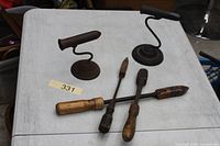 Overall lot showing two cast iron stands and three soldering irons on tabletop