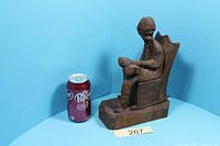 Front angle view showing full carved man in rocking chair with soda can for scale