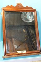 Full view of rectangular mirror with wood frame and scalloped top