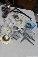 Wide view showing assorted brackets, hinges, swivel bearings, sink strainer, wire ring and packaged hardware
