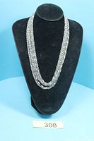 Full view of silver-tone nine-strand twisted chain sautoir necklace displayed on stand