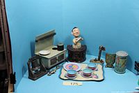 All items grouped: tea set, stove, bartender bank, parrot bank, bell, brass shield, opener