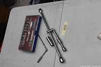 Closed socket set case alongside chrome lug and breaker bars on table