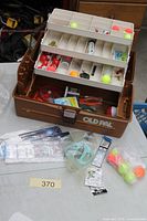 Open Old Pal tackle box displaying trays with various floats, hooks, lures, and spools