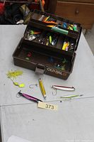 Closed tackle box open showing trays with lures