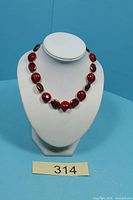Full view of red glass bead necklace displayed on white bust