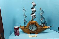 Front view of wooden ship clock beside soda can for scale