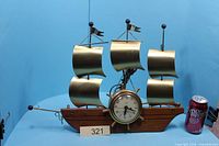 Front view of ship-shaped clock beside soda can for scale