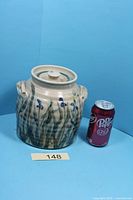 Front view of stoneware jar beside soda can for scale