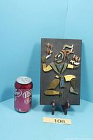 Full view of plaque on stand with soda can for scale