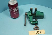Overall view of green vise beside soda can for scale
