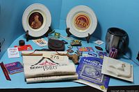 Overview of lot showing plates, towel, mugs, patches and accessories