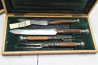 Open case showing four stag-handle utensils in green velvet lining