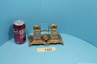 Full view of brass double inkwell set beside soda can for scale