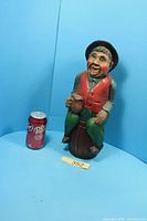 Front view of carved wooden figure next to soda can for scale